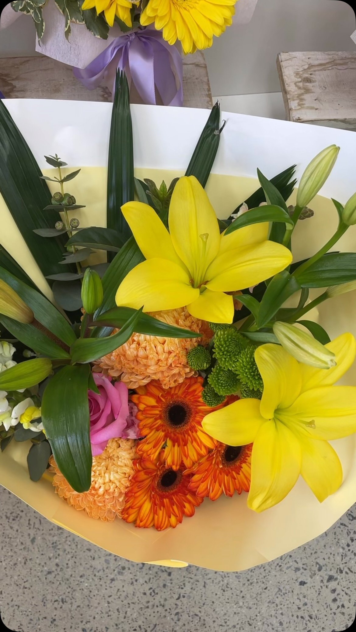Bright yellow lilies and orange blooms in a hand-tied bouquet